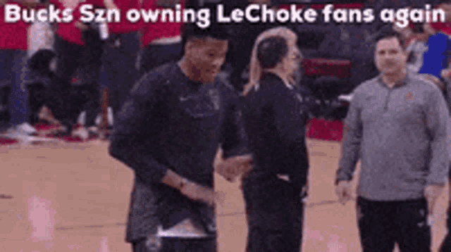 a man shakes hands with another man on a basketball court