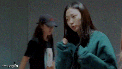 a woman in a green sweater is standing next to another woman in a black shirt .