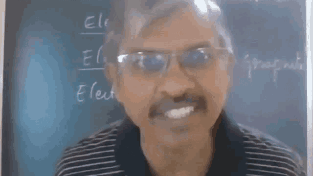 a man wearing glasses stands in front of a blackboard that says electro