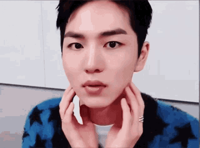 a young man is touching his face with his hands and making a funny face .