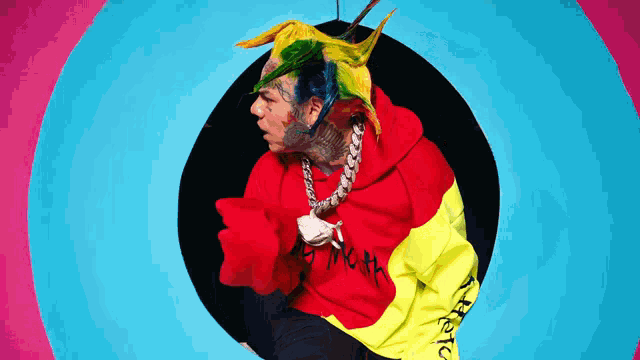 a man wearing a red yellow and blue hoodie with the word sixnine on it