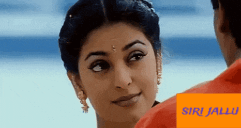 a woman with a bindi on her forehead is smiling and looking at a man