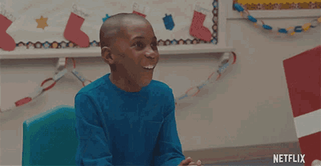 a boy in a blue shirt is laughing in front of a netflix banner