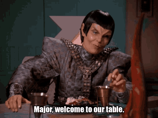 a woman sitting at a table with the words major welcome to our table written below her
