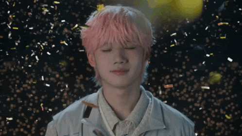 a young man with pink hair is surrounded by confetti and has his eyes closed