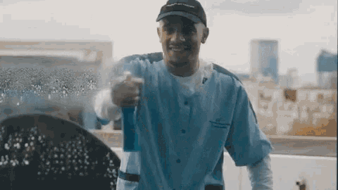 a man wearing a hat that says ' abercrombie & fitch ' on it sprays something
