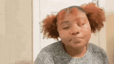 a woman with red hair is making a funny face while wearing a sweater .