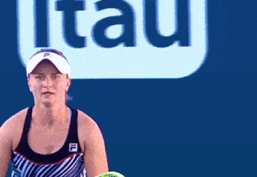 a tennis player wearing a white visor is serving a tennis ball