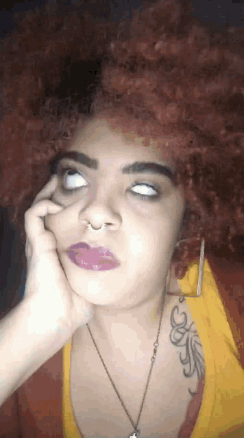 a woman with red hair is making a funny face with her hand on her face .