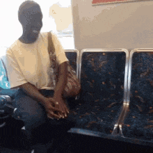 a man sits on a bus with a purse on his shoulder