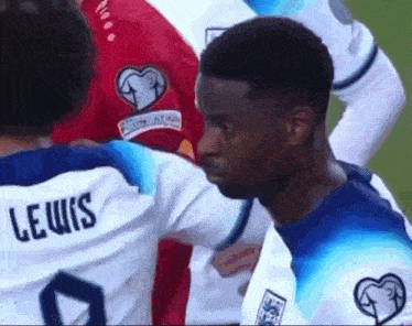 a soccer player wearing a lewis jersey talks to another player