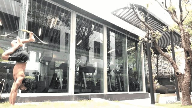 a man is doing a handstand in front of a gym with a video playing in the background