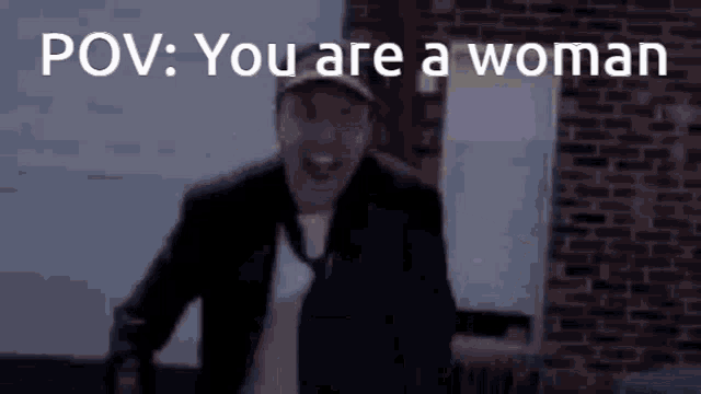 a man in a suit and tie is standing in front of a brick wall with the words pov : you are a woman