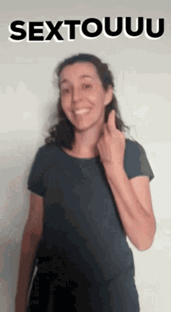 a woman in a black shirt is giving the middle finger in front of a sign that says sextouuuu