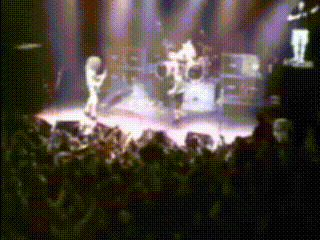a group of people playing instruments on a stage with a crowd watching