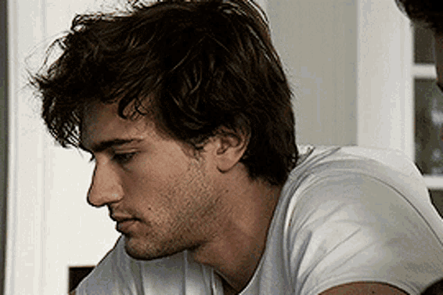 a man with brown hair and a beard is wearing a white t-shirt