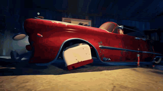 a red car is sitting in a garage with a cooler on the ground