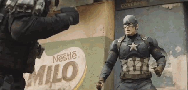 a man in a captain america costume is standing next to a nestle milo sign .