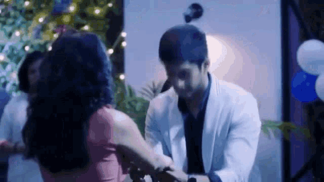a man and a woman are dancing together in a room with balloons .