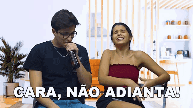 a man singing into a microphone next to a woman who is laughing and the words cara não adianta