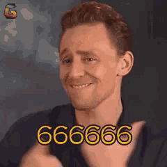 a man in a black shirt is smiling and making a funny face with the number 666 on his chest .