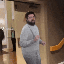 a man with glasses and a beard is standing in front of a yellow door