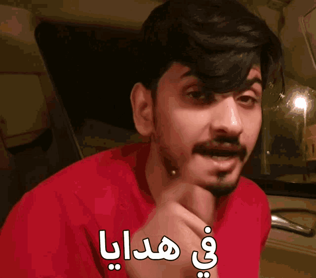 a man wearing a red shirt has arabic writing on his shirt