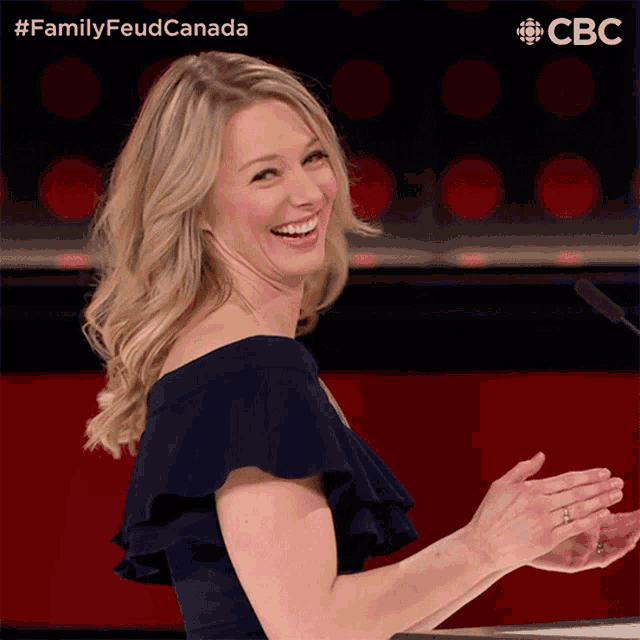 a woman in a blue dress is smiling and clapping in front of a cbs sign