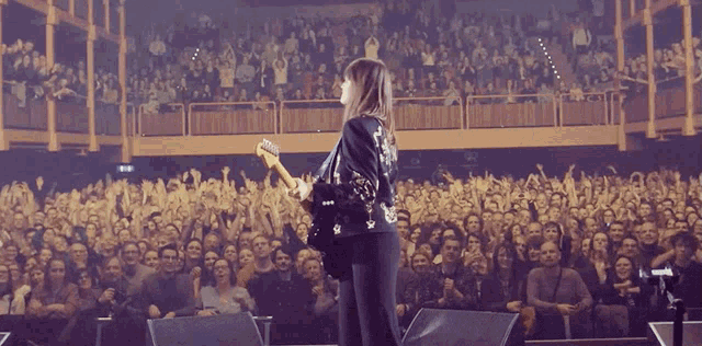 a woman plays a guitar in front of a crowd