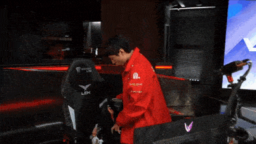 a man in a red jacket is standing next to a chair that says lck