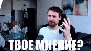 a man with a beard is talking into a microphone while sitting on a couch in a living room .