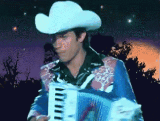 a man in a cowboy hat is playing a keyboard