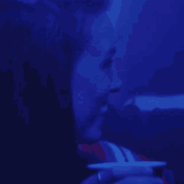 a close up of a person 's face with a blue light behind them .