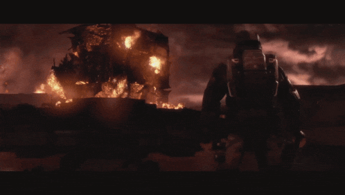 a man in a gas mask stands in front of a building on fire