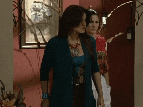 a woman in a blue cardigan is standing next to another woman in a red shirt