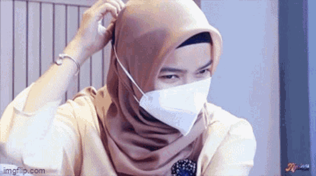 a woman wearing a hijab and a face mask