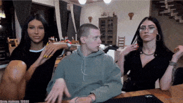 a man and two women are sitting at a table with the number 10000 on the bottom left