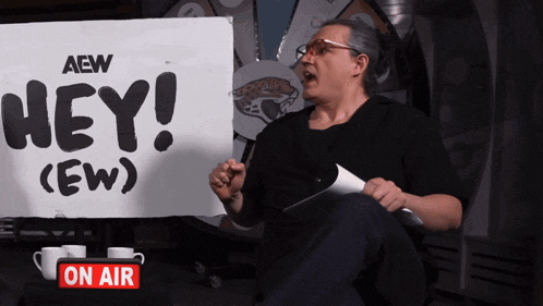 a man sits in front of a sign that says hey