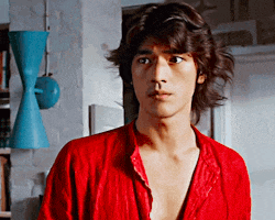 a young man in a red shirt is standing in a room