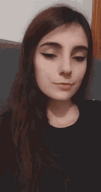 a close up of a woman 's face with long hair and a black shirt .