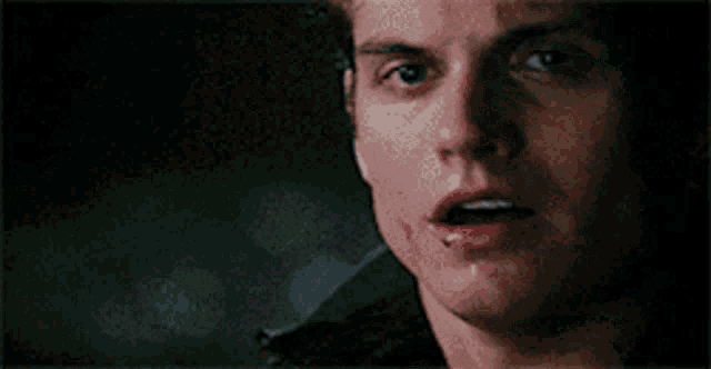 a close up of a young man 's face with his mouth open and a blurry background .