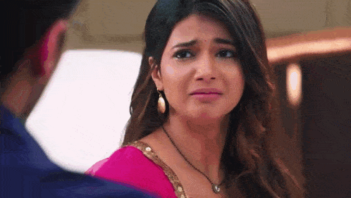 a woman in a pink sari is crying while looking at a man .