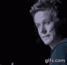 a close up of a man wearing a microphone on his face in a dark room .