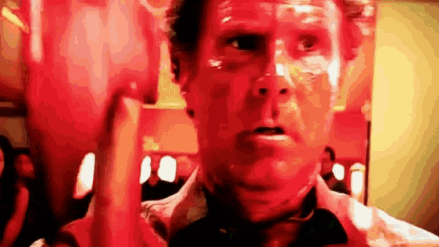 a man with red paint on his face is holding a glass of wine in his hand .
