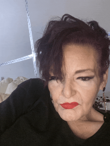 a woman wearing red lipstick and a black shirt looks at the camera