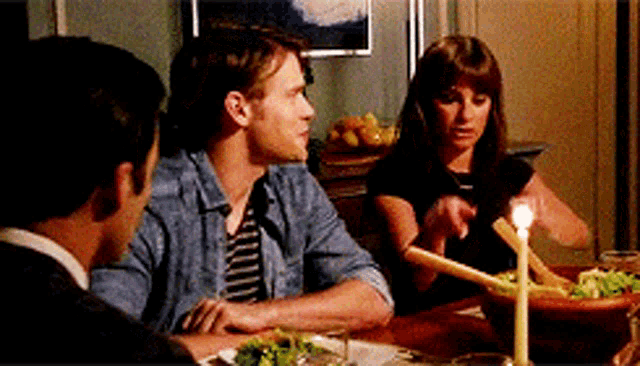 a group of people are sitting at a table with a candle