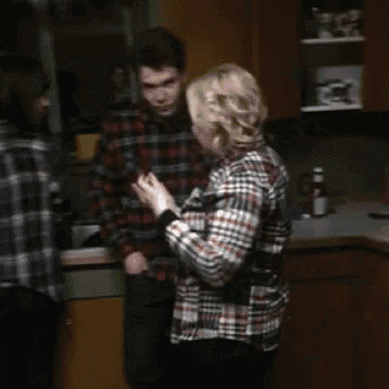 a woman in a plaid shirt is standing next to a man in a plaid shirt in a kitchen