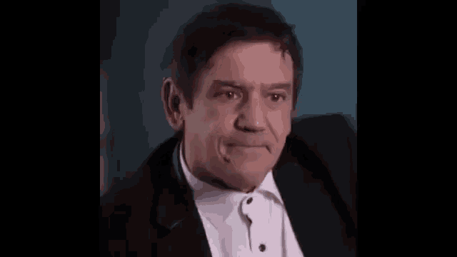 a man in a tuxedo and bow tie is making a funny face .
