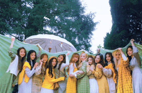 a group of girls are posing for a picture while holding umbrellas and blankets