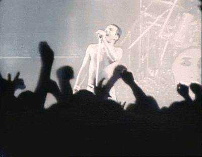 a man singing into a microphone in front of a crowd of people